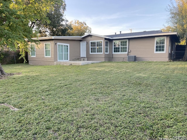 rear view of property featuring central AC and a yard