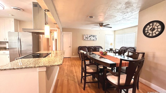 dining area with ceiling fan, a textured ceiling, and light wood-type flooring