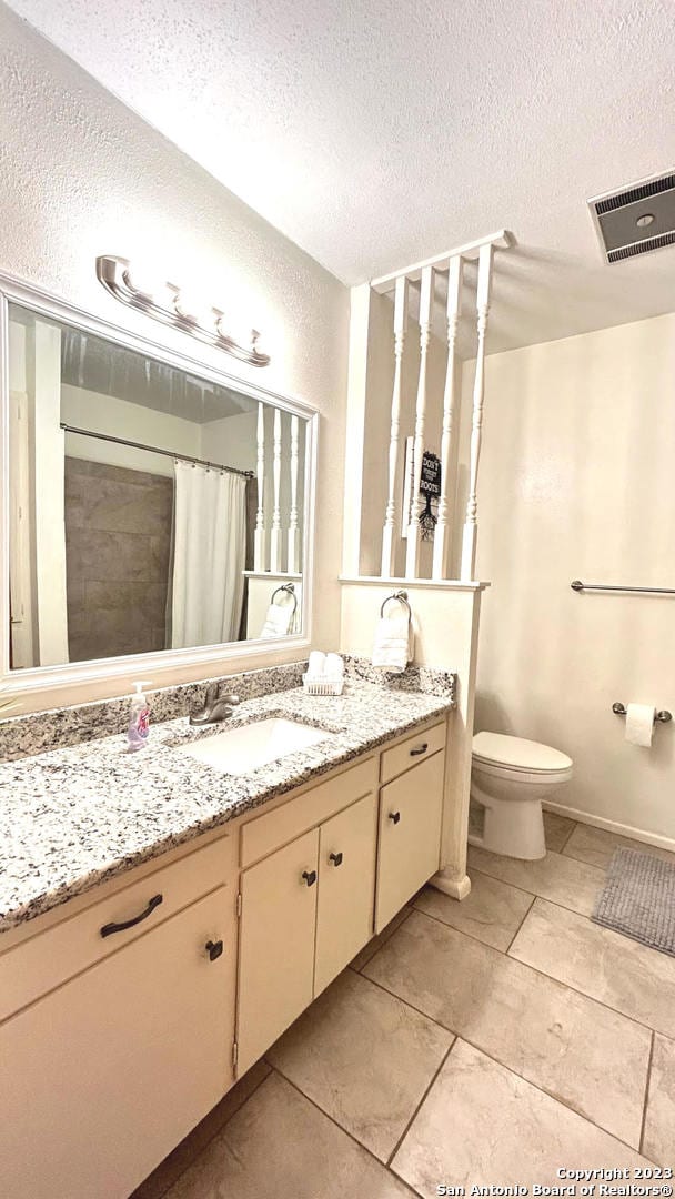 bathroom with toilet, walk in shower, tile patterned flooring, vanity, and a textured ceiling