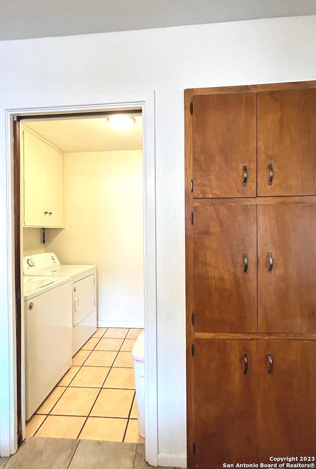 laundry room featuring cabinets, light tile patterned floors, and independent washer and dryer