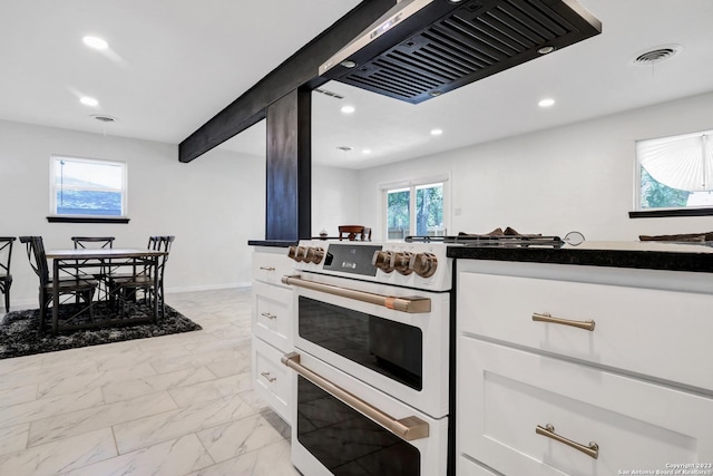 kitchen featuring double oven range, range hood, and white cabinets