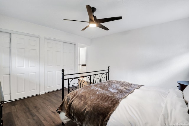 bedroom featuring multiple closets, dark wood-type flooring, and ceiling fan