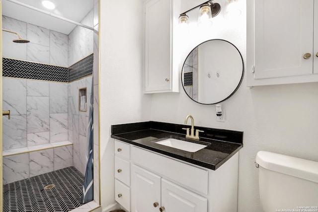 bathroom with vanity, tiled shower, and toilet