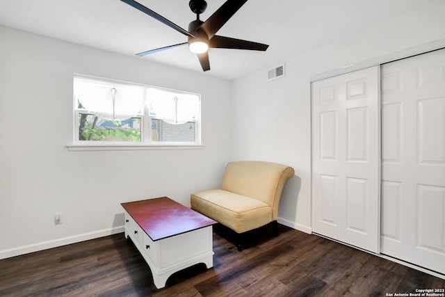 living area featuring dark wood-type flooring and ceiling fan