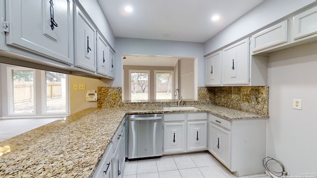 kitchen with sink, white cabinetry, light stone counters, stainless steel dishwasher, and backsplash