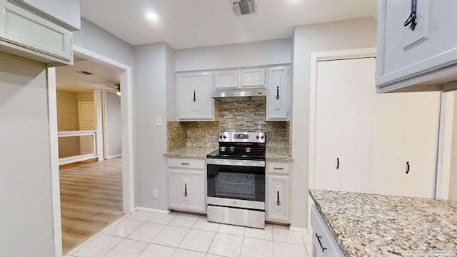 kitchen featuring light tile patterned floors, ceiling fan, stainless steel range with electric stovetop, backsplash, and light stone countertops