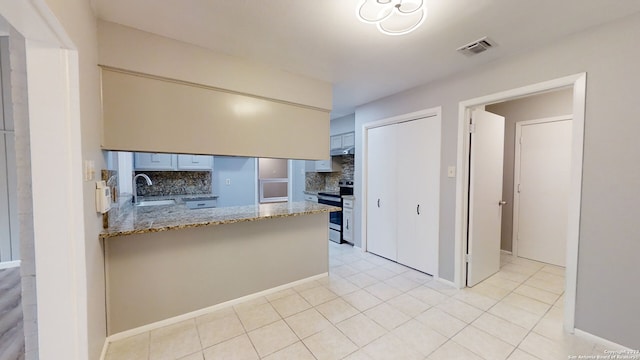 kitchen featuring tasteful backsplash, sink, stainless steel range with electric cooktop, kitchen peninsula, and light stone countertops