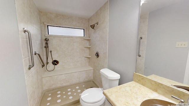 bathroom featuring vanity, a tile shower, and toilet