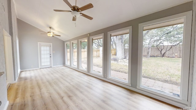 unfurnished sunroom featuring vaulted ceiling, a healthy amount of sunlight, and ceiling fan