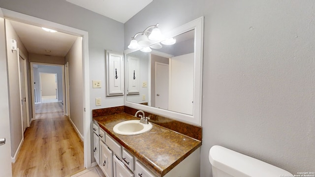 bathroom with hardwood / wood-style flooring, vanity, and toilet