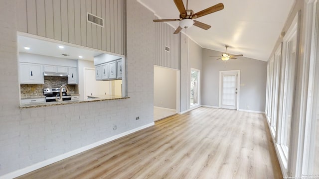 unfurnished living room with high vaulted ceiling, ceiling fan, and light wood-type flooring