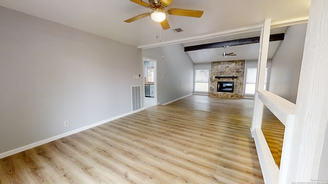 unfurnished living room featuring lofted ceiling with beams, a stone fireplace, ceiling fan, and light hardwood / wood-style floors