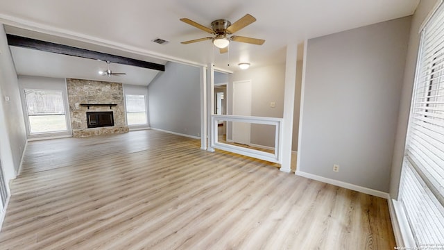 unfurnished living room featuring ceiling fan, a fireplace, lofted ceiling with beams, and light hardwood / wood-style flooring