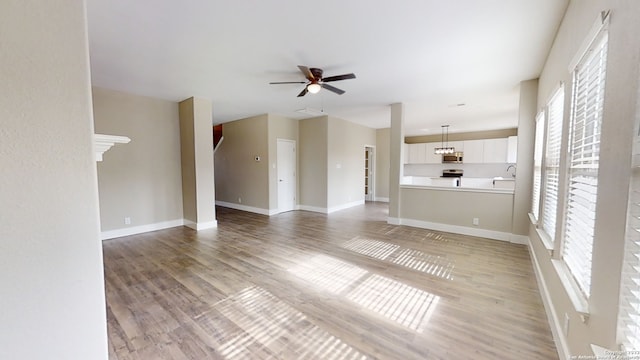 unfurnished living room featuring ceiling fan, sink, and hardwood / wood-style floors