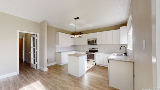 kitchen with decorative light fixtures, white cabinetry, sink, a center island, and stainless steel appliances