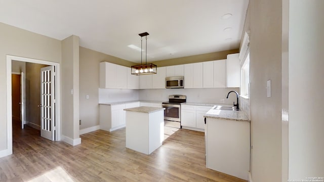 kitchen with sink, white cabinetry, stainless steel appliances, a center island, and decorative light fixtures