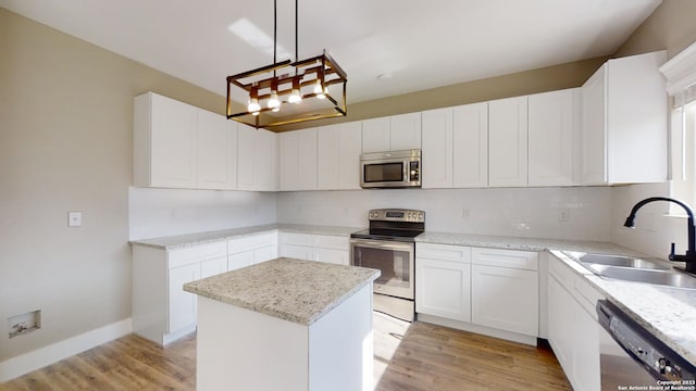 kitchen featuring sink, a center island, hanging light fixtures, stainless steel appliances, and white cabinets