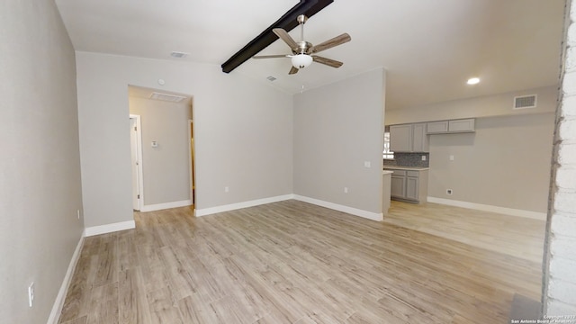 unfurnished living room featuring vaulted ceiling with beams, light hardwood / wood-style flooring, and ceiling fan