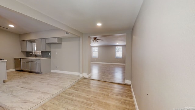 kitchen featuring sink, gray cabinetry, decorative backsplash, ceiling fan, and light wood-type flooring