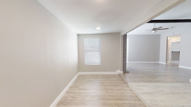 empty room featuring beamed ceiling, ceiling fan, and light hardwood / wood-style flooring