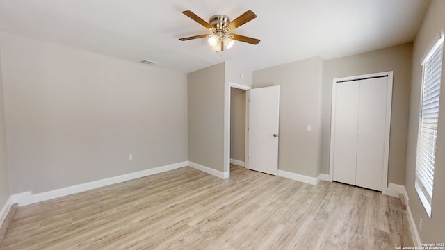 unfurnished bedroom with multiple windows, light hardwood / wood-style flooring, ceiling fan, and a closet