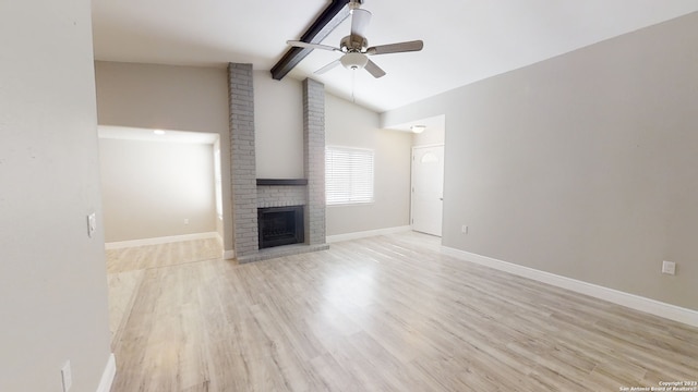 unfurnished living room featuring vaulted ceiling with beams, a fireplace, light hardwood / wood-style floors, and ceiling fan