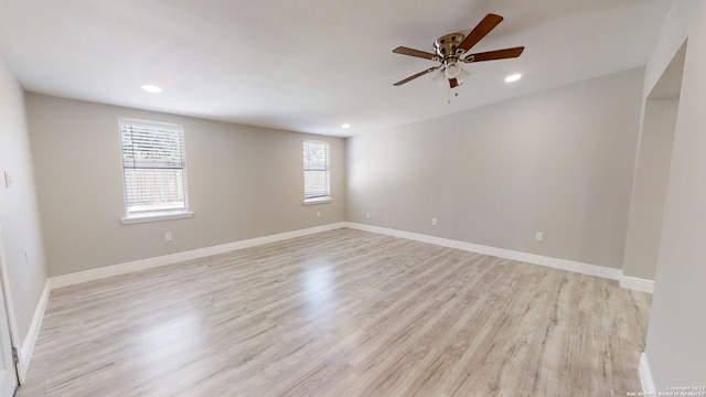 spare room featuring ceiling fan, light wood-type flooring, and a wealth of natural light