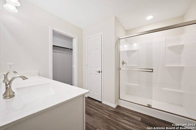 bathroom with a shower with shower door, vanity, and hardwood / wood-style flooring