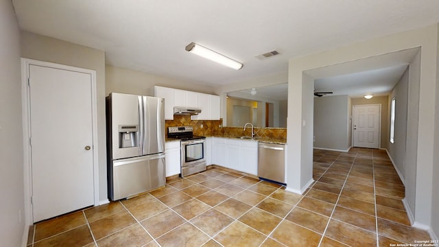 kitchen featuring appliances with stainless steel finishes, sink, white cabinets, backsplash, and light stone countertops