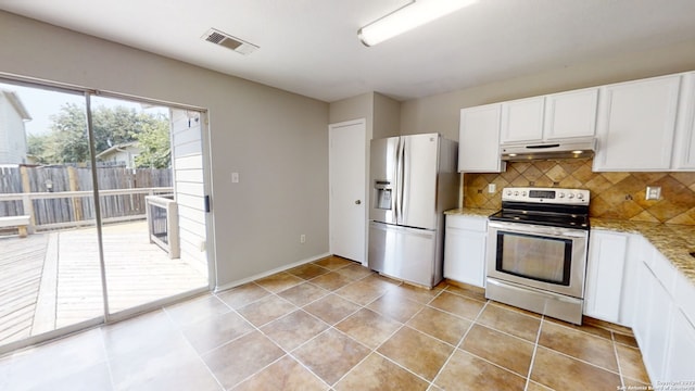 kitchen with light tile patterned floors, appliances with stainless steel finishes, white cabinetry, tasteful backsplash, and light stone countertops