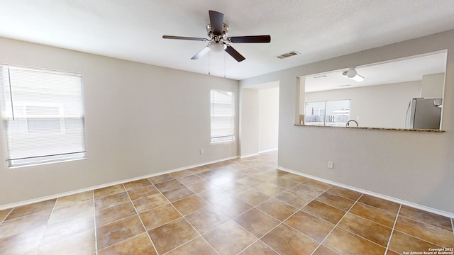 tiled empty room featuring plenty of natural light, sink, and ceiling fan