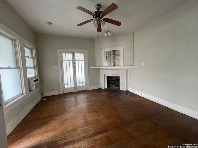 unfurnished living room with a fireplace, cooling unit, ceiling fan, dark wood-type flooring, and french doors