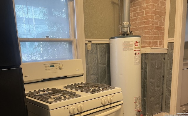 kitchen with black refrigerator, water heater, and white range with gas stovetop