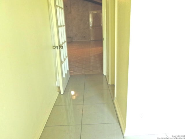 hall featuring baseboards and tile patterned floors