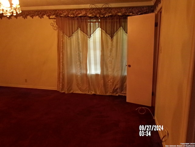 carpeted empty room featuring a chandelier