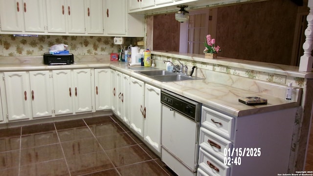 kitchen with light countertops, a sink, white cabinetry, white dishwasher, and dark tile patterned flooring