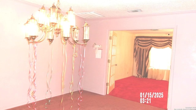 hallway with carpet floors, a textured ceiling, visible vents, and crown molding