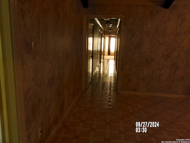 hall with dark parquet flooring and wooden walls