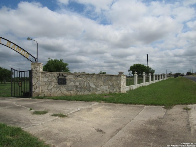 community / neighborhood sign with a lawn, a gate, and fence