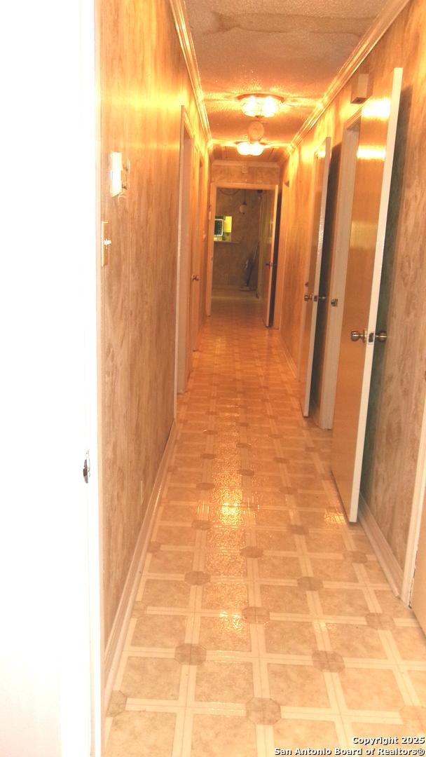 hallway featuring ornamental molding and wooden walls