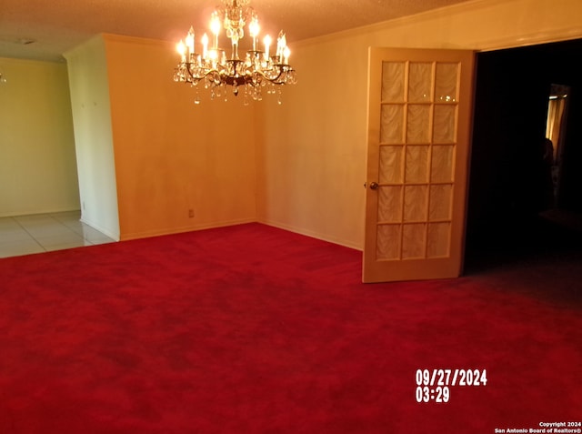 carpeted empty room featuring ornamental molding and a chandelier