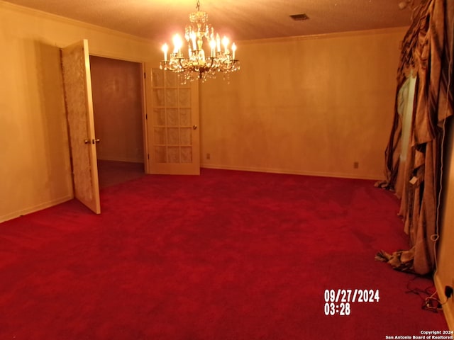 carpeted empty room with ornamental molding, a notable chandelier, and a textured ceiling