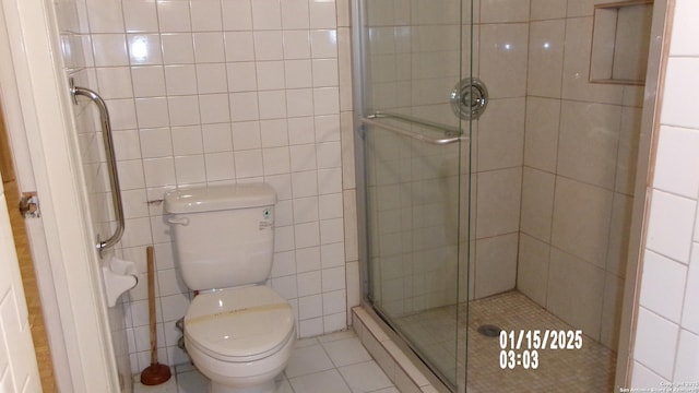 full bathroom featuring tile walls, toilet, tile patterned flooring, and a shower stall