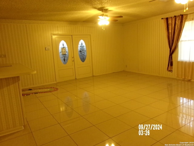 tiled entrance foyer with a textured ceiling and ceiling fan