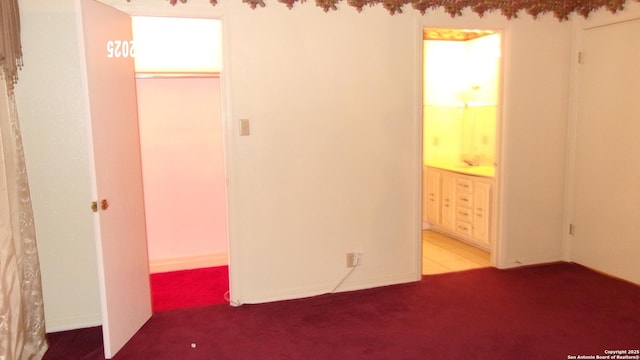 unfurnished bedroom featuring ensuite bathroom and carpet flooring