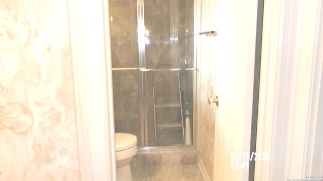 full bath with toilet and a stall shower