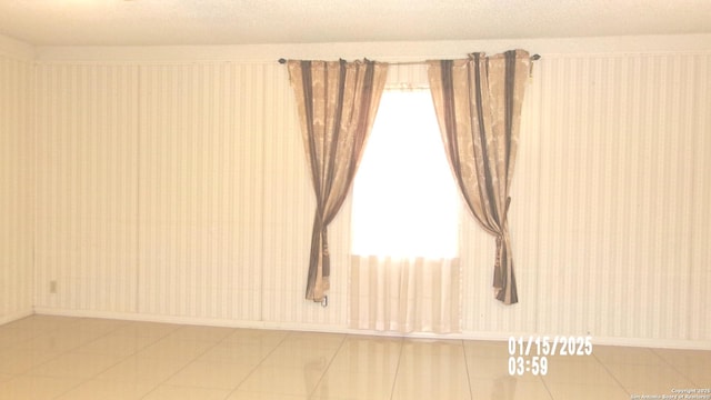 empty room featuring a textured ceiling and tile patterned floors