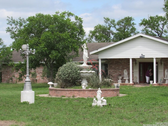 exterior space featuring brick siding, a shingled roof, and a front lawn
