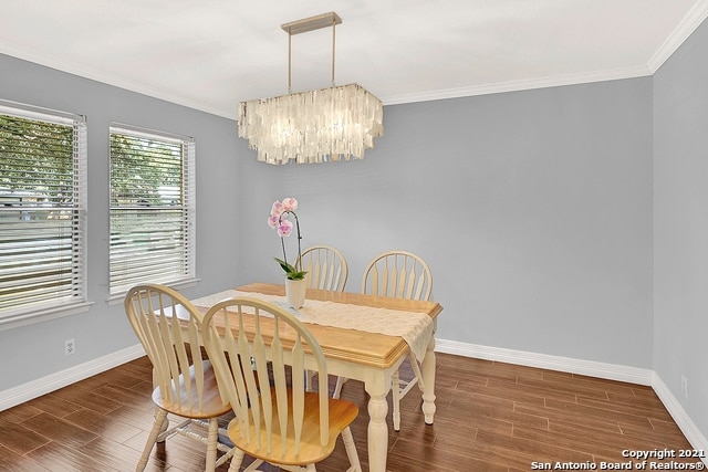 dining room with ornamental molding, dark hardwood / wood-style flooring, and a chandelier