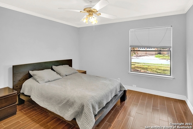 bedroom with crown molding, hardwood / wood-style floors, and ceiling fan